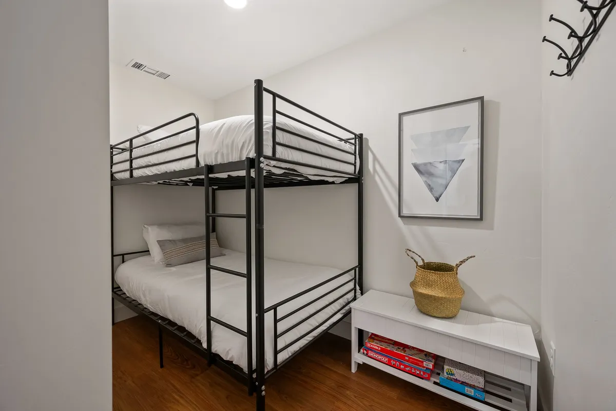 A cheerful bunk room with a queen-over-queen bunk bed, decorative wall art, a storage bench, and soft furnishings. The inviting space is designed for comfort, with plenty of room for families or groups to relax, play games, or enjoy a bedtime story.