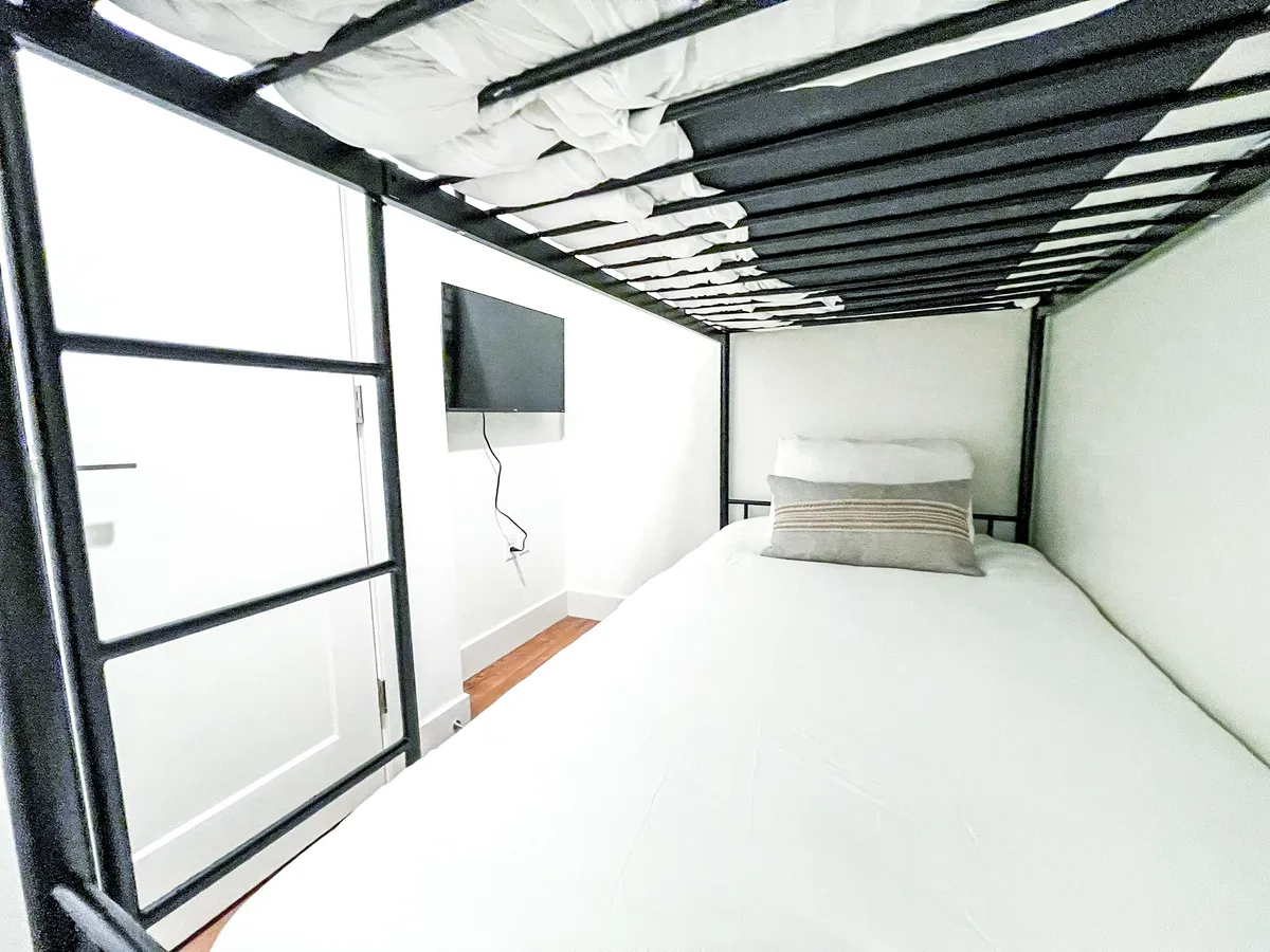 A cozy bonus bunk space with twin bunks, a decorative pillow, and a wall-mounted TV. The intimate atmosphere makes it perfect for younger guests or multi-generational stays, offering a separate corner for relaxing or watching movies.